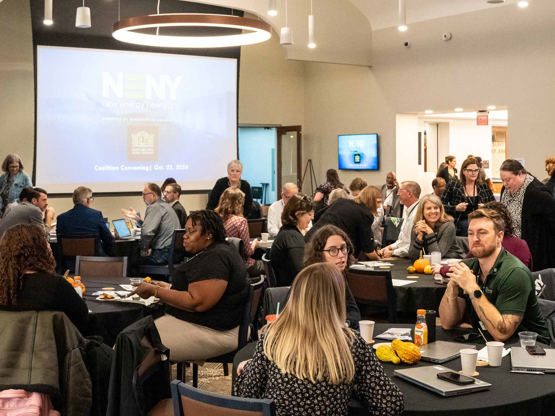 Many people seated at several round tables at the New Energy New York Coalition Convening