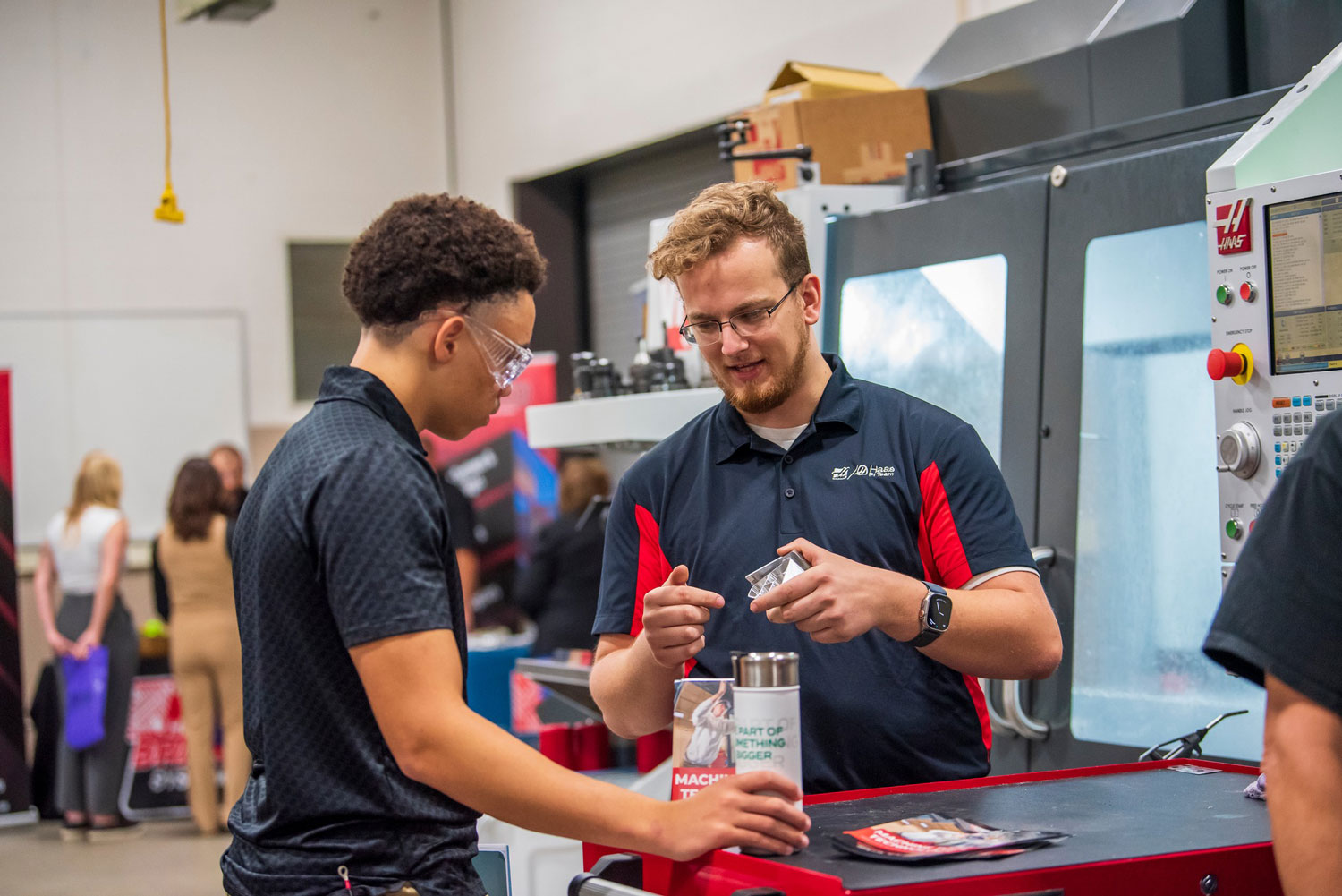 Two students discussing their work in a manufacturing facility